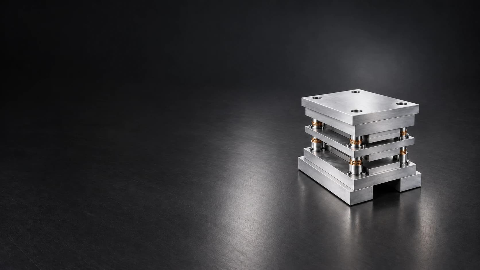 Steel die set with ground plates, guide pillars and bronze guide bushes on a dark charcoal floor